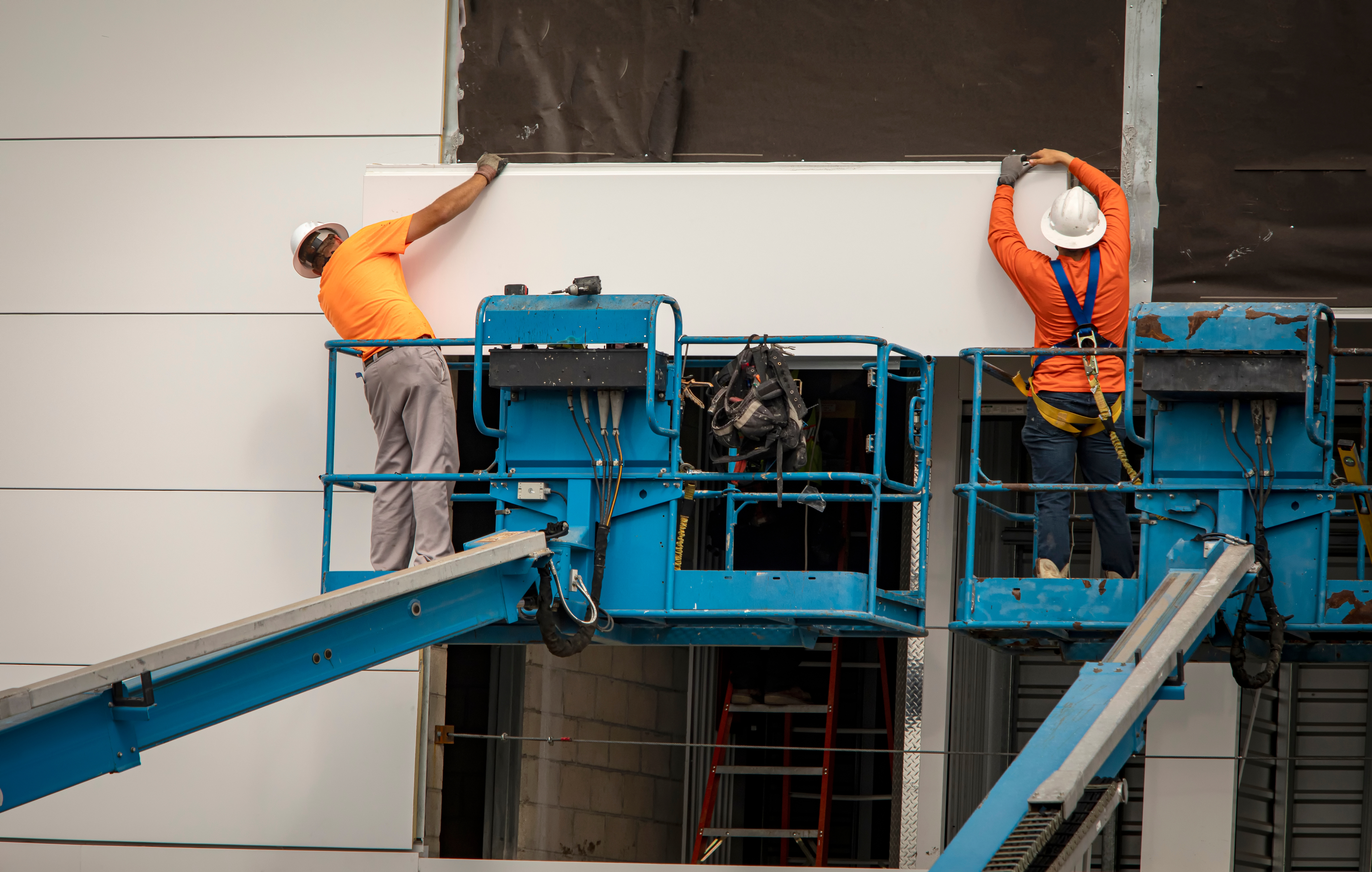 Two construction workers install a prefabricated panel on site